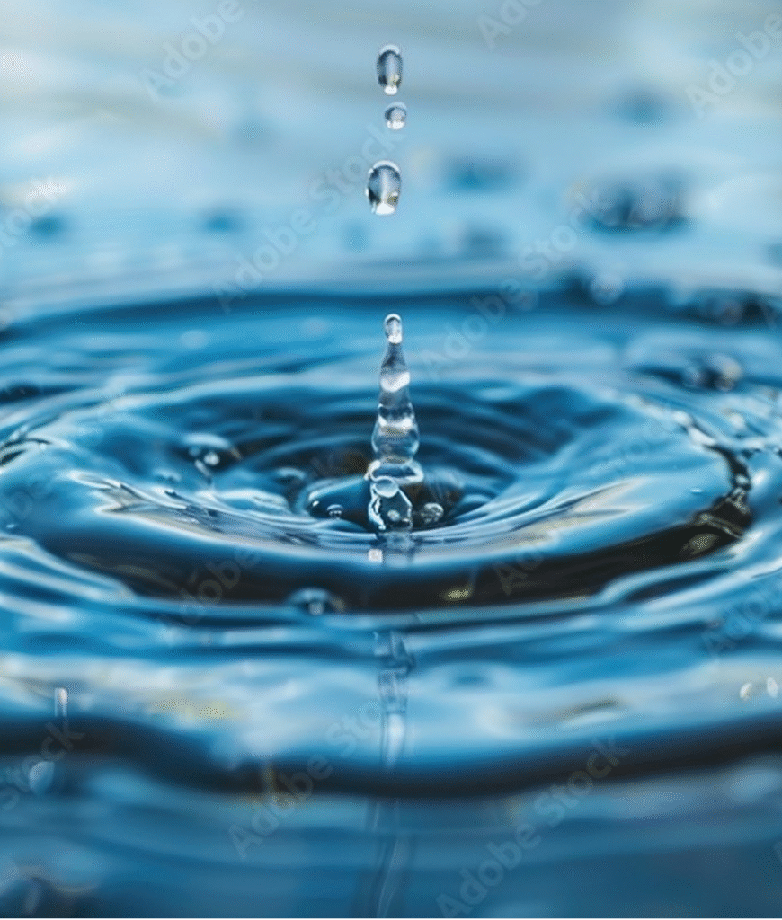 Ein fallender Wassertropfen erzeugt konzentrische Wellen auf einer ruhigen Wasseroberfläche, während sich weitere Tropfen darüber befinden.